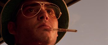 Movie still from “Fear and Loathing in Las Vegas” (1998), directed by Terry Gilliam – A person wearing a hat and smoking a cigarette; Extreme Close Up shot, Low angle