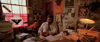 Movie still from “Fear and Loathing in Las Vegas” (1998), directed by Terry Gilliam – A man sitting at a desk in front of papers; Medium shot, High angle