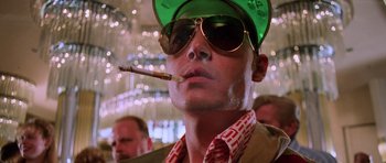 Movie still from “Fear and Loathing in Las Vegas” (1998), directed by Terry Gilliam – A man in a green hat and sunglasses smoking a cigarette; Close Up shot, Low angle