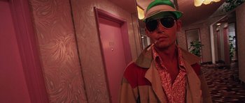 Movie still from “Fear and Loathing in Las Vegas” (1998), directed by Terry Gilliam – A man with a green hat smoking a cigarette in front of a pink door; Close Up shot, Low angle
