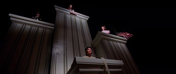 Movie still from “Fear and Loathing in Las Vegas” (1998), directed by Terry Gilliam – A woman standing at a podium in front of a building; Wide shot, Low angle