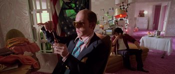Movie still from “Fear and Loathing in Las Vegas” (1998), directed by Terry Gilliam – A man in a suit and sunglasses holding a cell phone; Medium shot, Low angle