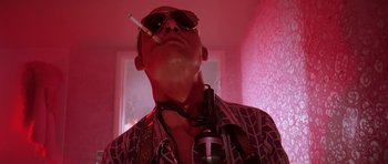 Movie still from “Fear and Loathing in Las Vegas” (1998), directed by Terry Gilliam – A man wearing sunglasses and smoking a cigarette in a room; Close Up shot, Low angle