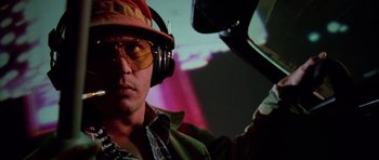 Movie still from “Fear and Loathing in Las Vegas” (1998), directed by Terry Gilliam – A man wearing headphones and sunglasses while looking at the camera; Close Up shot, Low angle