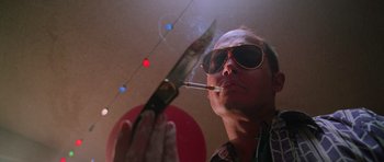 Movie still from “Fear and Loathing in Las Vegas” (1998), directed by Terry Gilliam – A man smoking a cigarette while holding a knife in front of him; Close Up shot, Low angle