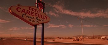Movie still from “Fear and Loathing in Las Vegas” (1998), directed by Terry Gilliam – A red and white sign that reads " drive here fully back soon "; Extreme Wide shot, Low angle