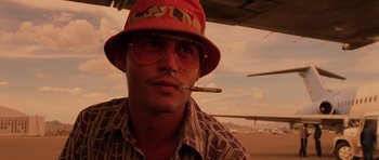 Movie still from “Fear and Loathing in Las Vegas” (1998), directed by Terry Gilliam – A man wearing a red hat smoking a cigarette; Close Up shot, Low angle