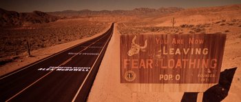 Movie still from “Fear and Loathing in Las Vegas” (1998), directed by Terry Gilliam – An image of a road that has a sign on the side of the road; Extreme Wide shot, Low angle
