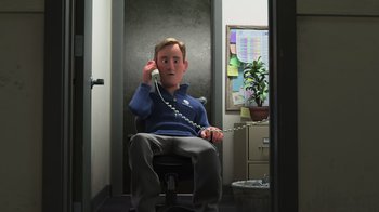 Movie still from “Finding Dory” (2016), directed by Angus MacLane – A man sitting in a chair holding a phone to his ear; Medium shot, High angle