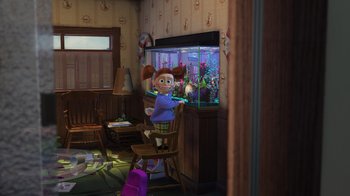 Movie still from “Finding Nemo” (2003), directed by Andrew Stanton – A girl is sitting in front of a fish tank in a living room; Wide shot, High angle