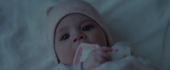 Movie still from “Firestarter” (2022), directed by Keith Thomas – A baby wearing a pink hat; Extreme Close Up shot, High angle