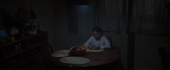 Movie still from “Firestarter” (2022), directed by Keith Thomas – A woman sitting at a table looking at her cell phone; Wide shot, High angle