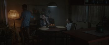 Movie still from “Firestarter” (2022), directed by Keith Thomas – Two women sitting at a table in a dark room; Wide shot, High angle