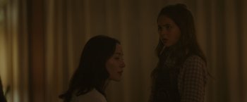 Movie still from “Firestarter” (2022), directed by Keith Thomas – Two young women standing next to each other in a dimly - lit room; Medium shot, Over the shoulder angle