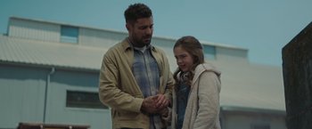 Movie still from “Firestarter” (2022), directed by Keith Thomas – A man and a girl holding hands in front of a building; Medium shot, Over the shoulder angle