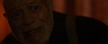 Movie still from “Firestarter” (2022), directed by Keith Thomas – An old man with a beard is smiling for the camera; Close Up shot, High angle