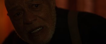 Movie still from “Firestarter” (2022), directed by Keith Thomas – An old man with a piercing is looking at the camera; Extreme Close Up shot, High angle