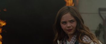 Movie still from “Firestarter” (2022), directed by Keith Thomas – A young girl is standing in front of a fire; Close Up shot, Over the shoulder angle