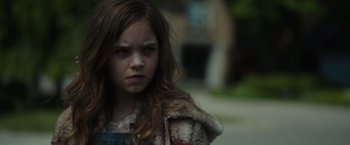 Movie still from “Firestarter” (2022), directed by Keith Thomas – A young girl with long brown hair wearing a plaid shirt; Close Up shot, Over the shoulder angle