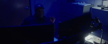 Movie still from “Firestarter” (2022), directed by Keith Thomas – A man sitting in front of two computer monitors; Medium shot, Low angle