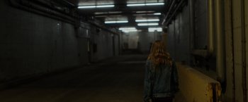 Movie still from “Firestarter” (2022), directed by Keith Thomas – A woman in a denim jacket walking in an empty building; Wide shot, High angle