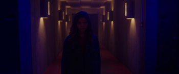 Movie still from “Firestarter” (2022), directed by Keith Thomas – A woman standing in a dark hallway with lights on; Medium shot, Low angle
