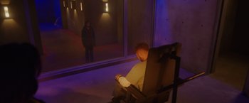 Movie still from “Firestarter” (2022), directed by Keith Thomas – A man sitting in a chair in front of a woman; Wide shot, High angle