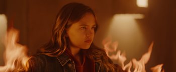 Movie still from “Firestarter” (2022), directed by Keith Thomas – A young girl is looking at the camera; Close Up shot, Over the shoulder angle
