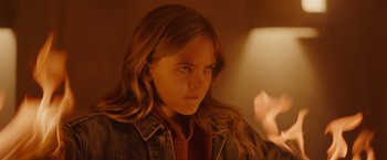 Movie still from “Firestarter” (2022), directed by Keith Thomas – A young girl with long brown hair is looking at the camera; Close Up shot, High angle