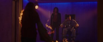 Movie still from “Firestarter” (2022), directed by Keith Thomas – A man and a woman are standing in front of a fire; Wide shot, Low angle