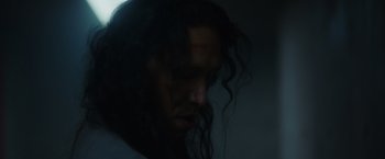 Movie still from “Firestarter” (2022), directed by Keith Thomas – A man with long black hair is looking down; Close Up shot, Low angle