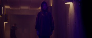Movie still from “Firestarter” (2022), directed by Keith Thomas – A person standing in a dark room wearing a hooded sweatshirt; Medium shot, Low angle