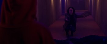 Movie still from “Firestarter” (2022), directed by Keith Thomas – A woman in a dark room holding something up; Medium shot, Over the shoulder angle