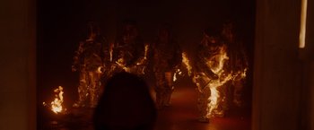 Movie still from “Firestarter” (2022), directed by Keith Thomas – A group of people standing in a room with fire; Wide shot, Low angle