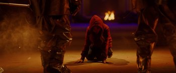 Movie still from “Firestarter” (2022), directed by Keith Thomas – A woman crouching on the ground in front of a fireplace; Wide shot, Over the shoulder angle
