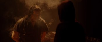 Movie still from “Firestarter” (2022), directed by Keith Thomas – A man standing next to another man in a dark room; Medium shot, Over the shoulder angle