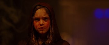 Movie still from “Firestarter” (2022), directed by Keith Thomas – A young girl wearing a hood with blood all over her face; Close Up shot, High angle