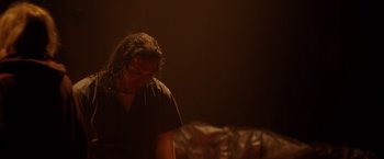 Movie still from “Firestarter” (2022), directed by Keith Thomas – A person in a dark room looking down at the ground; Medium shot, Low angle