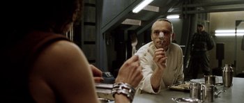 Movie still from “Alien: Resurrection” (1997), directed by Jean-Pierre Jeunet – A man holding a fork in front of a woman; Close Up shot, Over the shoulder angle