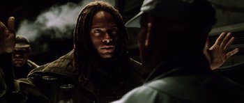 Movie still from “Alien: Resurrection” (1997), directed by Jean-Pierre Jeunet – A man with dreadlocks is talking to another man; Close Up shot, Low angle