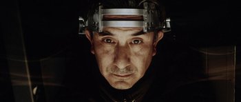 Movie still from “Alien: Resurrection” (1997), directed by Jean-Pierre Jeunet – A man wearing a metal head piece with a dark background; Close Up shot, Low angle