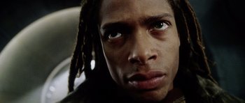 Movie still from “Alien: Resurrection” (1997), directed by Jean-Pierre Jeunet – A person with dreadlocks looking at the camera; Close Up shot, Low angle