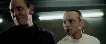 Movie still from “Alien: Resurrection” (1997), directed by Jean-Pierre Jeunet – Two men standing next to each other in front of a wall; Close Up shot, Low angle