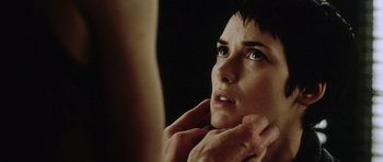 Movie still from “Alien: Resurrection” (1997), directed by Jean-Pierre Jeunet – A woman looking into a mirror while touching her face; Close Up shot, Over the shoulder angle