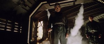 Movie still from “Alien: Resurrection” (1997), directed by Jean-Pierre Jeunet – A man in a uniform standing next to a building; Medium shot, Low angle