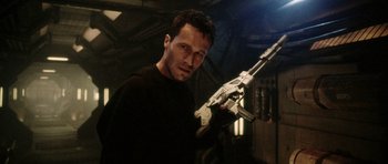 Movie still from “Alien: Resurrection” (1997), directed by Jean-Pierre Jeunet – A man holding a gun while wearing a black t - shirt; Close Up shot, Low angle