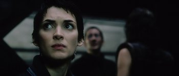 Movie still from “Alien: Resurrection” (1997), directed by Jean-Pierre Jeunet – A woman looking up at the camera while two other people look on; Close Up shot, Over the shoulder angle