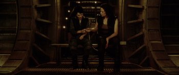 Movie still from “Alien: Resurrection” (1997), directed by Jean-Pierre Jeunet – Two people sitting on a bench looking at each other; Medium shot, High angle