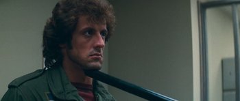 Movie still from “First Blood” (1982), directed by Ted Kotcheff – A person holding a stick in his mouth; Close Up shot, Low angle