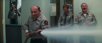 Movie still from “First Blood” (1982), directed by Ted Kotcheff – Two men in police uniforms are holding a fire hose; Medium shot, Over the shoulder angle